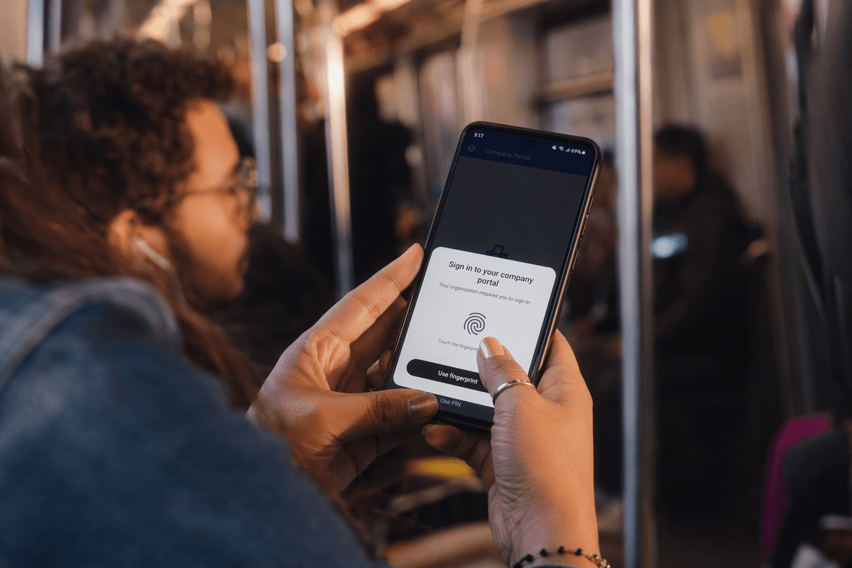 Gros plan sur des mains tenant un téléphone Android qui affiche une fenêtre d’approbation de passkey par empreinte digitale pour se connecter à un portail d’entreprise pendant un trajet